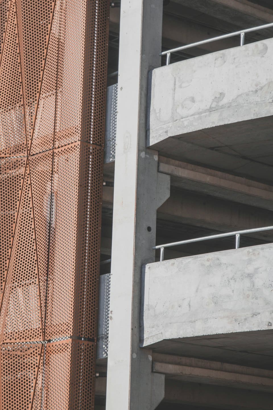 Facciata di un edificio moderno con elementi in metallo forato e cemento.