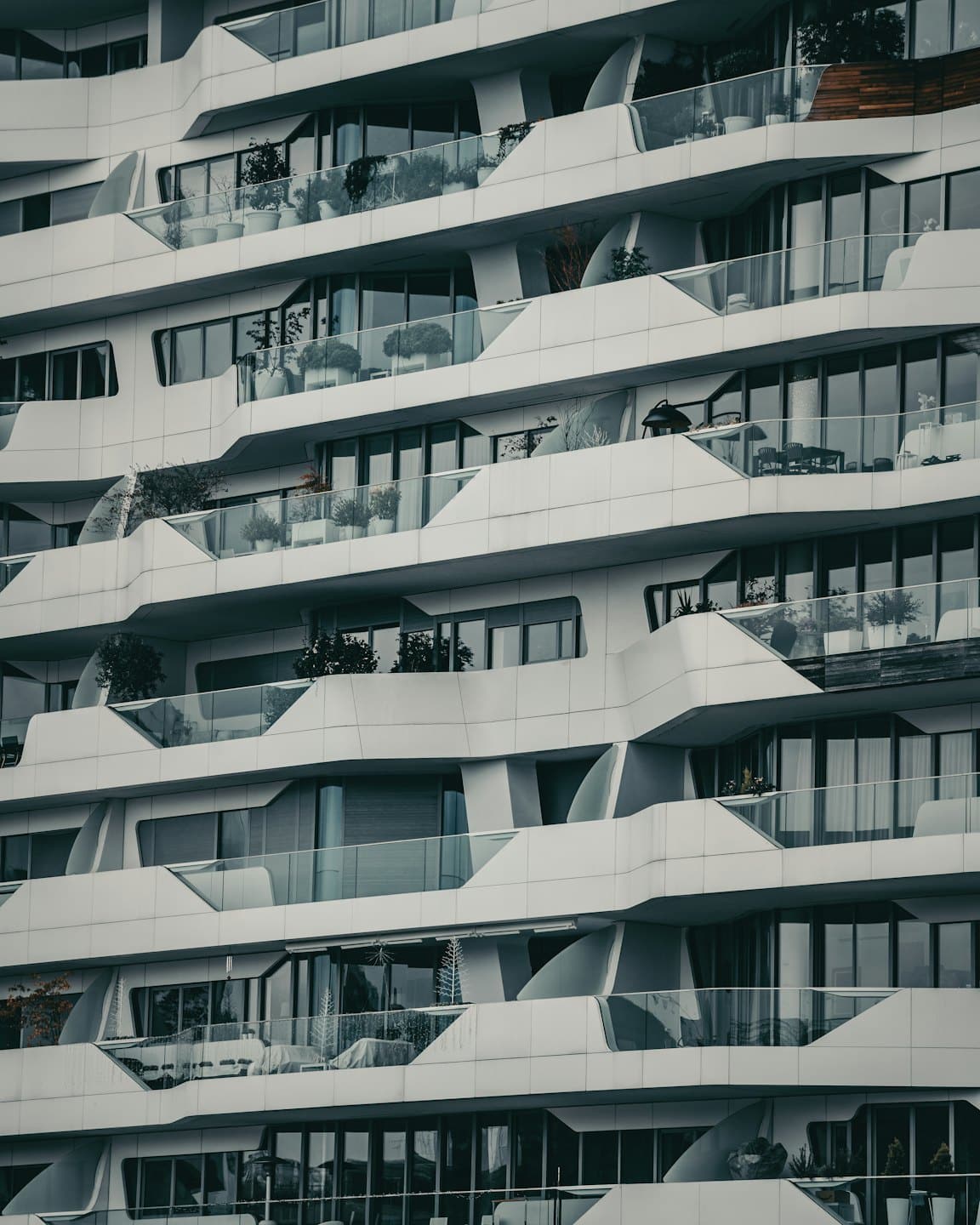 Moderno condominio con architettura curvilinea bianca e balconi in vetro.