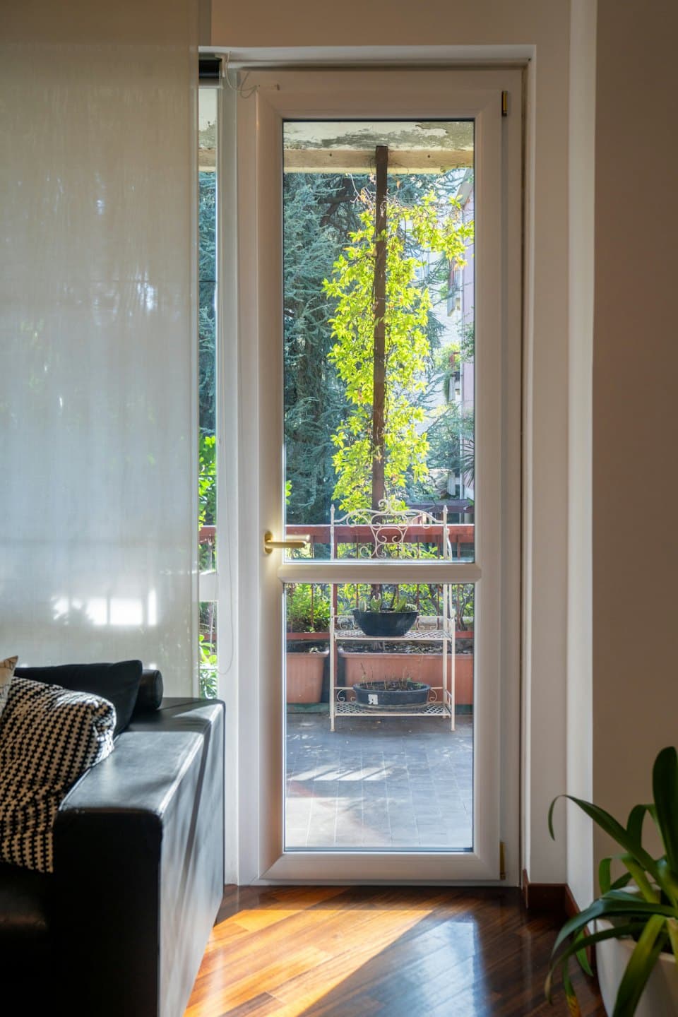 Spazio abitativo moderno che si affaccia su un balcone soleggiato con piante.